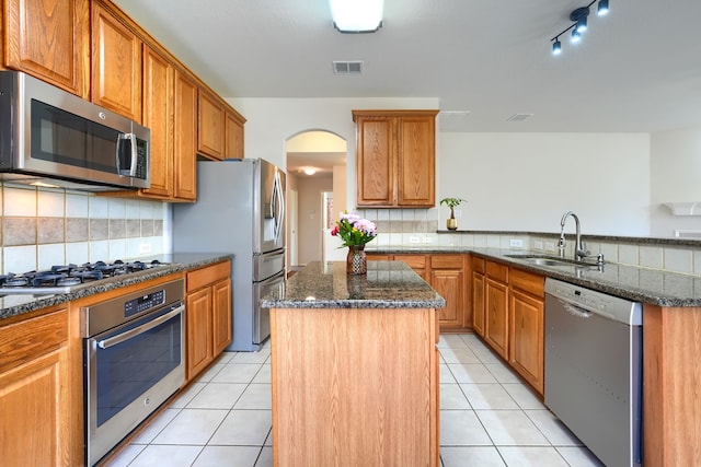 4424 Ridge Point Ln, Plano, TX 75024 - kitchen with stainless steel appliances, a center island, dark stone counters, and decorative backsplash