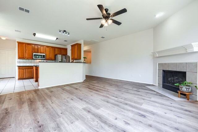 4424 Ridge Point Ln, Plano, TX 75024 - kitchen with appliances with stainless steel finishes, open floor plan, light wood finished floors, dark countertops, and brown cabinetry