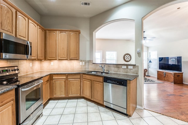 1138 Sophia St, Allen, TX 75013 - kitchen featuring stainless steel appliances, ceiling fan, arched walkways, tasteful backsplash, and dark stone counters