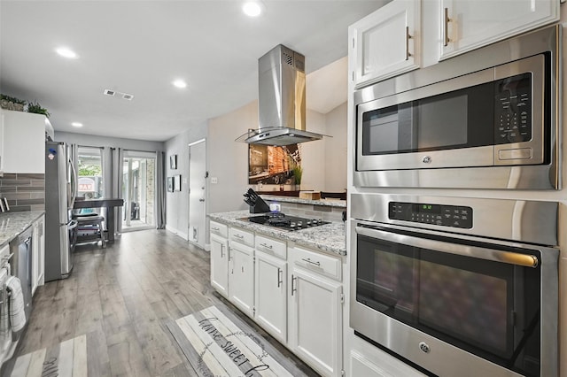 864 Warwick Dr, Plano, TX 75023 - kitchen featuring appliances with stainless steel finishes, island range hood, white cabinetry, light stone countertops, and recessed lighting