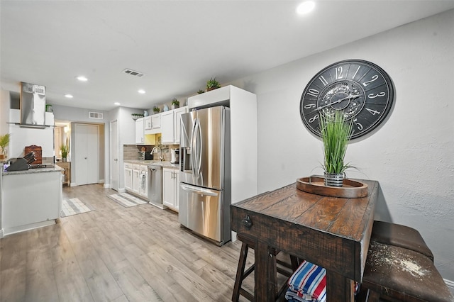 864 Warwick Dr, Plano, TX 75023 - kitchen featuring appliances with stainless steel finishes, range hood, white cabinets, light wood-style flooring, and recessed lighting