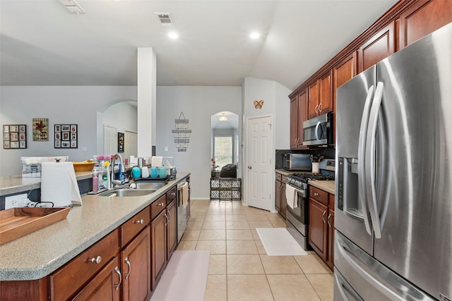 6436 Meadowcrest Ln, Sachse, TX 75048 - kitchen featuring appliances with stainless steel finishes, arched walkways, light tile patterned floors, vaulted ceiling, and light countertops