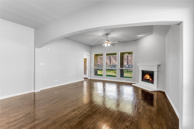 5608 Grove Cove Dr, Mckinney, TX 75071 - unfurnished living room with wood finished floors, ceiling fan, a glass covered fireplace, and arched walkways