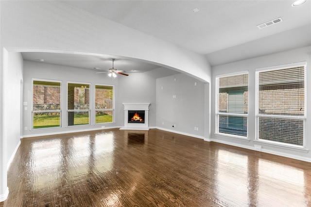 5608 Grove Cove Dr, Mckinney, TX 75071 - unfurnished living room with a ceiling fan, wood finished floors, a warm lit fireplace, vaulted ceiling, and arched walkways