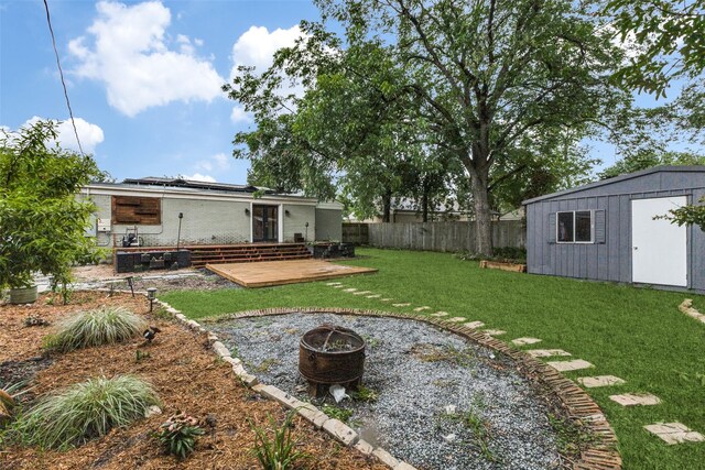 10649 Sylvia Dr, Dallas, TX 75228 - fenced backyard featuring a deck, a storage unit, and an outdoor fire pit