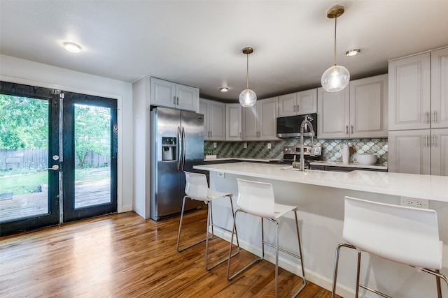 10649 Sylvia Dr, Dallas, TX 75228 - kitchen featuring stainless steel appliances, light countertops, decorative backsplash, and light wood-style floors