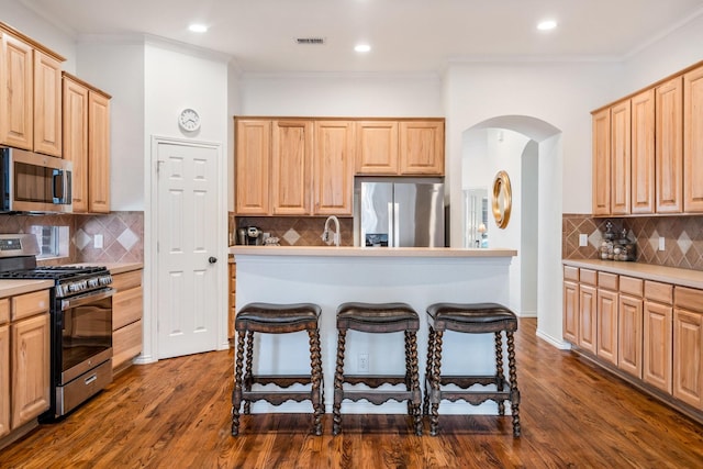 2484 Campfire Ln, Frisco, TX 75033 - kitchen featuring stainless steel appliances, light brown cabinets, backsplash, arched walkways, and ornamental molding