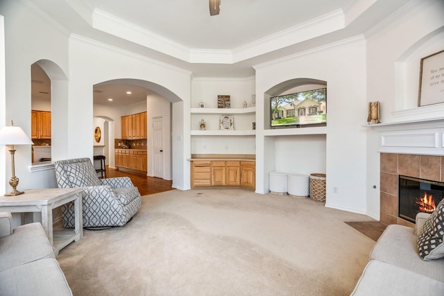 2484 Campfire Ln, Frisco, TX 75033 - living area with a fireplace, ornamental molding, a tray ceiling, light colored carpet, and built in shelves