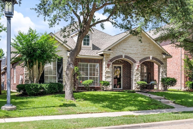 2484 Campfire Ln, Frisco, TX 75033 - view of front of home with stone siding, a shingled roof, a front yard, and brick siding