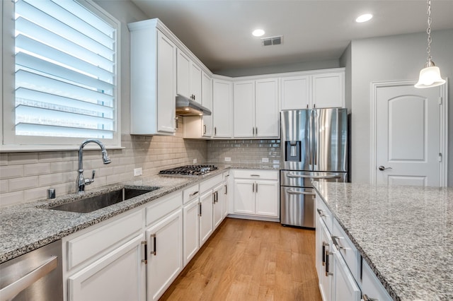 2129 Harbor Pointe Dr, Frisco, TX 75036 - kitchen with stainless steel appliances, under cabinet range hood, light wood finished floors, white cabinetry, and recessed lighting