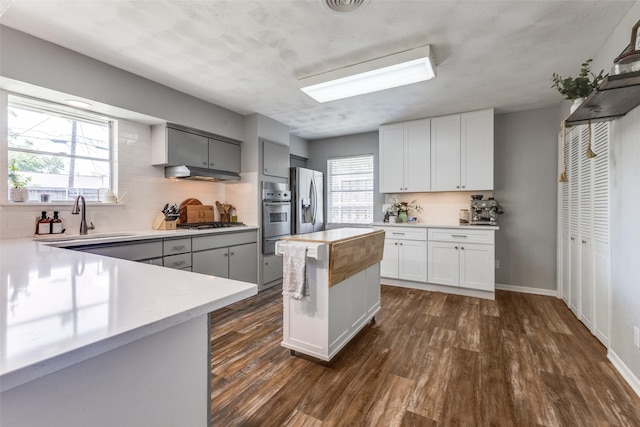 2521 Ridgecrest Dr, Garland, TX 75041 - kitchen featuring appliances with stainless steel finishes, a warming drawer, dark wood-style floors, decorative backsplash, and a kitchen island