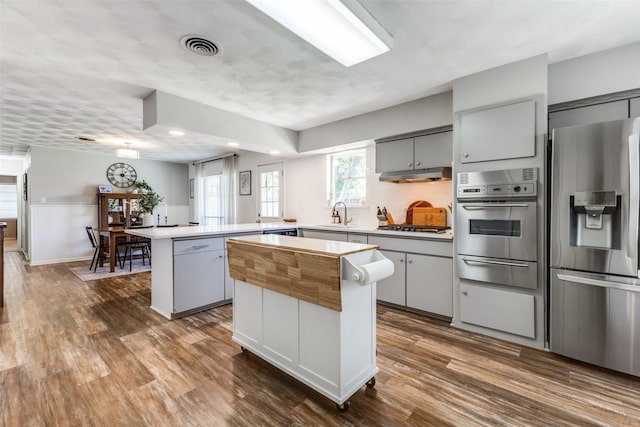 2521 Ridgecrest Dr, Garland, TX 75041 - kitchen featuring appliances with stainless steel finishes, a warming drawer, under cabinet range hood, a peninsula, and a center island