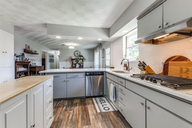 2521 Ridgecrest Dr, Garland, TX 75041 - kitchen featuring appliances with stainless steel finishes, light countertops, dark wood-type flooring, a peninsula, and backsplash