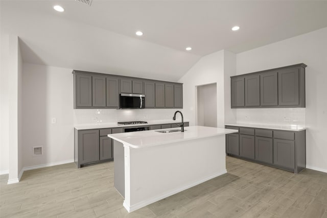733 Stone Eagle Dr, Azle, TX 76020 - kitchen with stainless steel microwave, vaulted ceiling, light wood finished floors, tasteful backsplash, and a kitchen island with sink