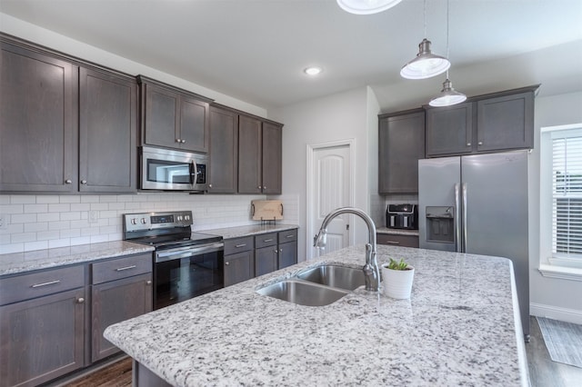 111 Arrowhead Dr, Sanger, TX 76266 - kitchen with stainless steel appliances, dark brown cabinetry, a kitchen island with sink, backsplash, and dark wood finished floors