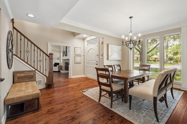 3217 Oak Tree Ln, Grapevine, TX 76051 - dining space featuring a chandelier, dark wood-style flooring, ornamental molding, stairway, and a fireplace