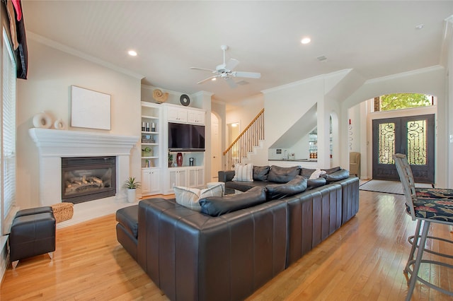 2327 Clearspring Dr N, Irving, TX 75063 - living area featuring ornamental molding, light wood-style flooring, stairway, a glass covered fireplace, and ceiling fan