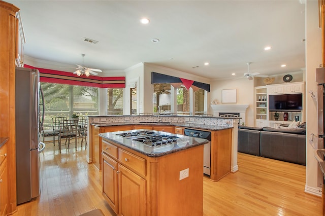2327 Clearspring Dr N, Irving, TX 75063 - kitchen with a ceiling fan, appliances with stainless steel finishes, a kitchen island, light wood finished floors, and crown molding