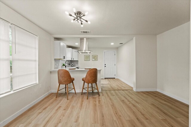 709 E Gandy St, Denison, TX 75021 - kitchen with island range hood, light countertops, a chandelier, light wood finished floors, and tasteful backsplash