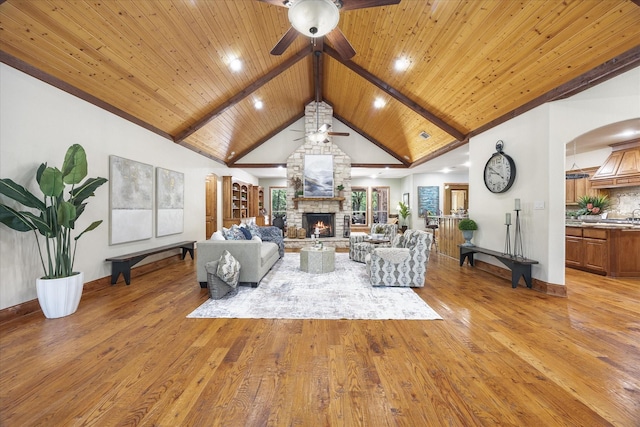 2702 Hidden Trails Rd, Royse City, TX 75189 - living room with a ceiling fan, light wood finished floors, a stone fireplace, a wooden ceiling with exposed beams, and arched walkways