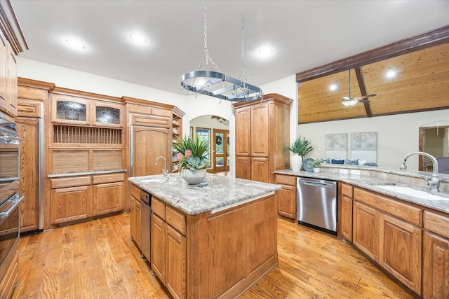 2702 Hidden Trails Rd, Royse City, TX 75189 - kitchen with dishwasher, light stone countertops, light wood-style flooring, an island with sink, and brown cabinetry