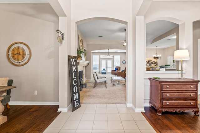 8601 Prescott Cir, Frisco, TX 75034 - entrance foyer featuring arched walkways, ceiling fan, a fireplace with raised hearth, carpet floors, and wood finished floors