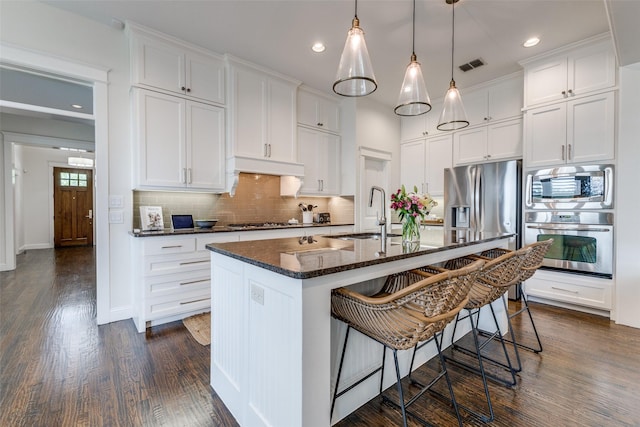 7204 Ripley St, Mckinney, TX 75071 - kitchen featuring appliances with stainless steel finishes, a kitchen bar, decorative backsplash, white cabinetry, and recessed lighting
