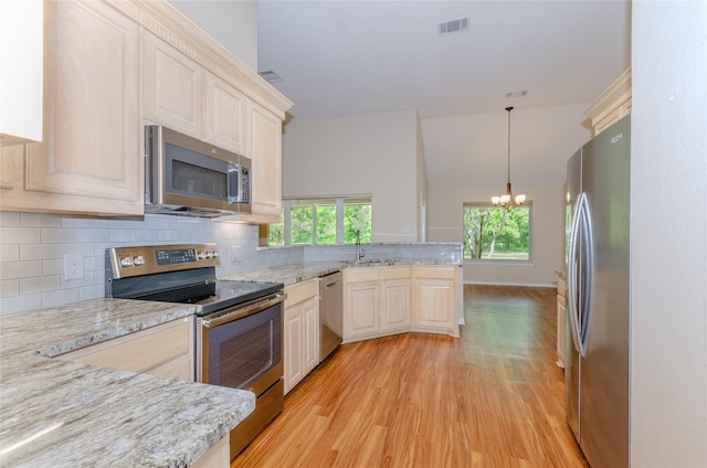 4720 Ashley Cir, Midlothian, TX 76065 - kitchen with stainless steel appliances, a peninsula, light wood-style flooring, decorative backsplash, and a chandelier