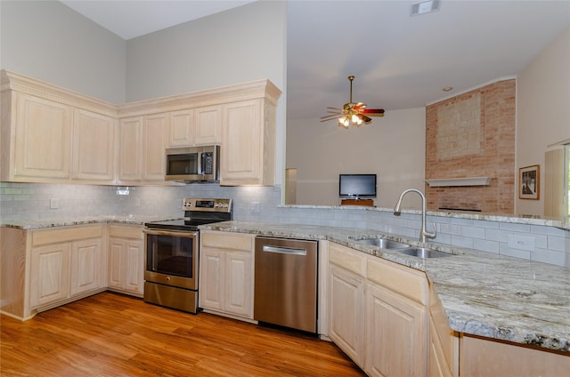 4720 Ashley Cir, Midlothian, TX 76065 - kitchen with stainless steel appliances, ceiling fan, a fireplace, backsplash, and light wood-style floors