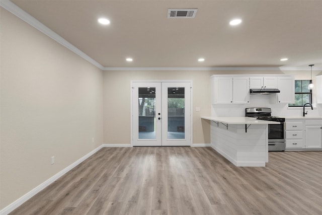 402 2nd St, Moody, TX 76557 - kitchen with stainless steel gas stove, crown molding, french doors, light countertops, and light wood finished floors
