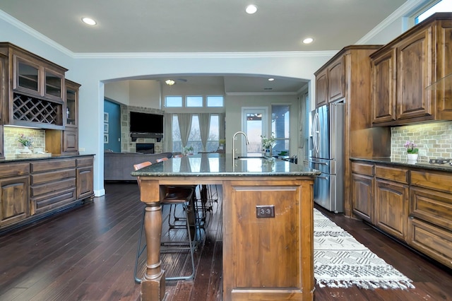 1844 Halifax St, Roanoke, TX 76262 - kitchen with stainless steel fridge with ice dispenser, arched walkways, a breakfast bar area, dark stone countertops, and ornamental molding