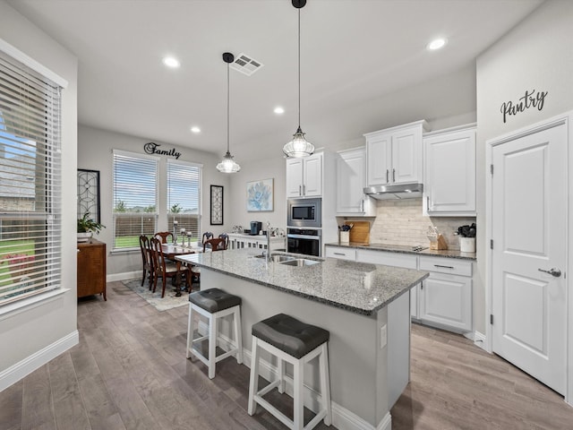 5622 Log Cabin Ct, Midlothian, TX 76065 - kitchen featuring appliances with stainless steel finishes, decorative backsplash, light wood finished floors, white cabinetry, and recessed lighting