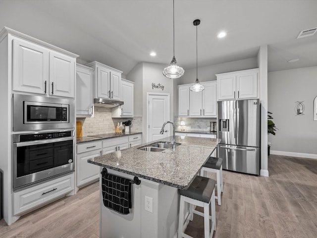 5622 Log Cabin Ct, Midlothian, TX 76065 - kitchen featuring appliances with stainless steel finishes, tasteful backsplash, an island with sink, white cabinetry, and recessed lighting