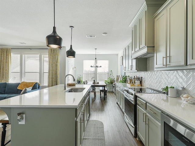 2309 Loch Ness Ln, Denton, TX 76207 - kitchen featuring stainless steel appliances, light countertops, decorative backsplash, dark wood finished floors, and an island with sink