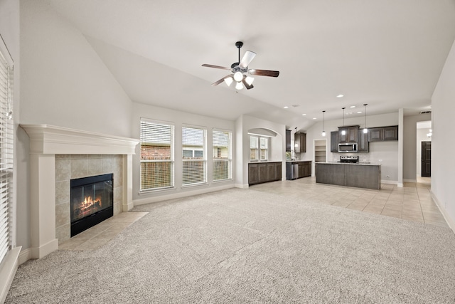 1020 Broken Wheel Trl, Aubrey, TX 76227 - unfurnished living room featuring lofted ceiling, light colored carpet, a ceiling fan, a tile fireplace, and light tile patterned flooring