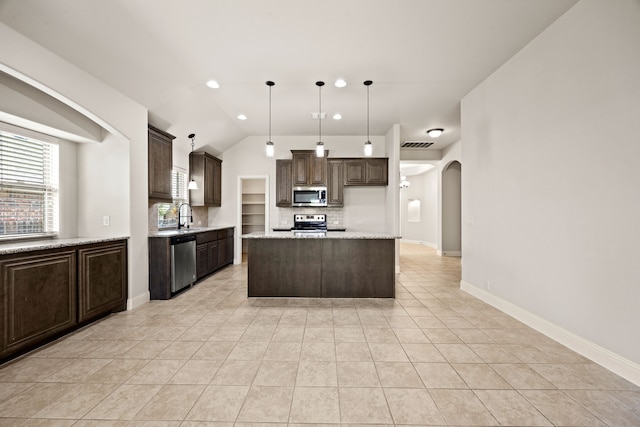 1020 Broken Wheel Trl, Aubrey, TX 76227 - kitchen with stainless steel appliances, arched walkways, dark brown cabinetry, tasteful backsplash, and light tile patterned floors