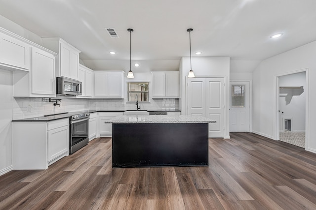 113 Aslan Rd, Poolville, TX 76487 - kitchen featuring stainless steel appliances, dark wood-style flooring, decorative backsplash, white cabinets, and a kitchen island