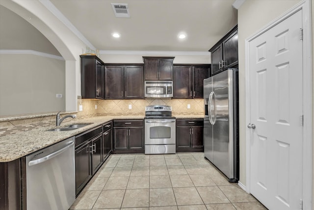 6525 Burling St, Woodway, TX 76712 - kitchen with appliances with stainless steel finishes, light stone countertops, backsplash, dark brown cabinets, and arched walkways