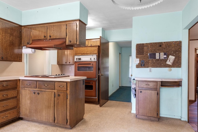 200 Hillcrest Ct, Irving, TX 75062 - kitchen with under cabinet range hood, stainless steel gas stovetop, double wall oven, a peninsula, and brown cabinets