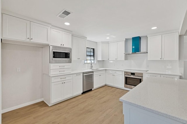 4103 Steeplewood Ct, Arlington, TX 76016 - kitchen with appliances with stainless steel finishes, wall chimney range hood, light wood-type flooring, white cabinetry, and recessed lighting
