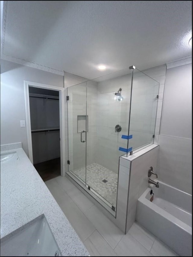 4103 Steeplewood Ct, Arlington, TX 76016 - bathroom with a stall shower, double vanity, a garden tub, a textured ceiling, and a walk in closet