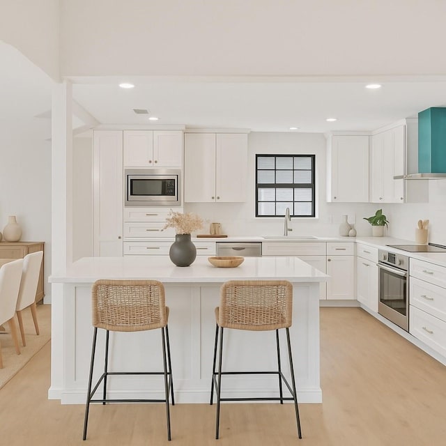 4103 Steeplewood Ct, Arlington, TX 76016 - kitchen featuring a sink, wall chimney exhaust hood, stainless steel appliances, a kitchen bar, and white cabinetry