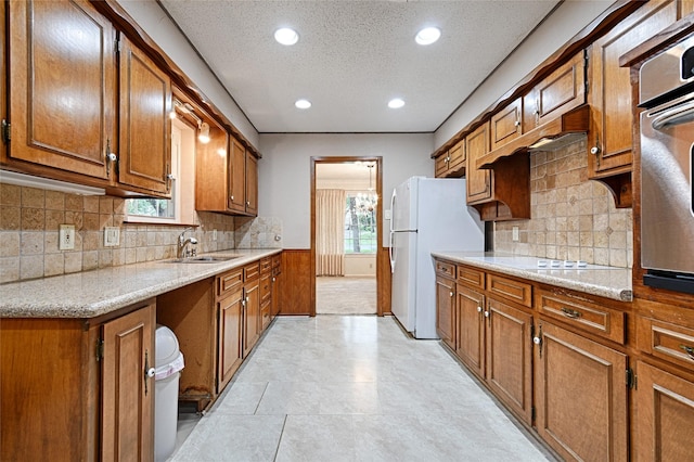 1013 Mountain Ter, Hurst, TX 76053 - kitchen featuring brown cabinetry, white appliances, a textured ceiling, recessed lighting, and tasteful backsplash