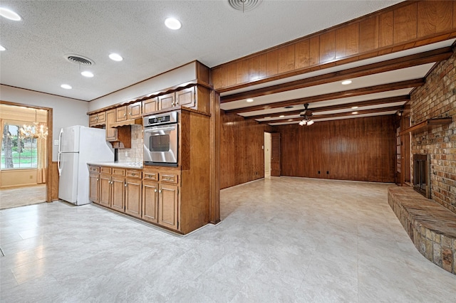 1013 Mountain Ter, Hurst, TX 76053 - kitchen with oven, freestanding refrigerator, wooden walls, brown cabinetry, and ceiling fan