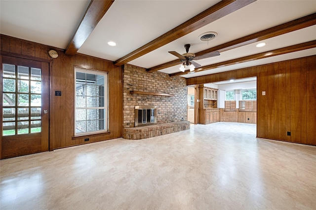 1013 Mountain Ter, Hurst, TX 76053 - unfurnished living room with wooden walls, ceiling fan, beam ceiling, a brick fireplace, and tile patterned floors