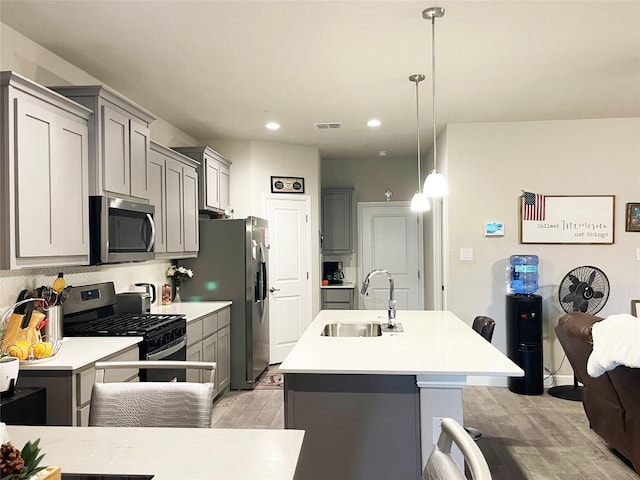 4107 Reese Ln, Krum, TX 76249 - kitchen featuring stainless steel appliances, gray cabinets, light wood-type flooring, a kitchen island with sink, and recessed lighting