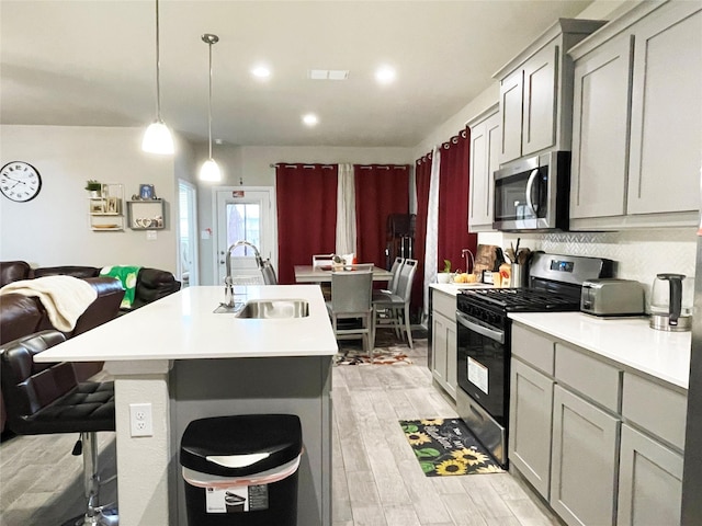 4107 Reese Ln, Krum, TX 76249 - kitchen featuring appliances with stainless steel finishes, light countertops, a center island with sink, open floor plan, and light wood-type flooring
