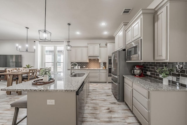 6340 Crossvine Trl, Flower Mound, TX 76226 - kitchen featuring stainless steel appliances, decorative backsplash, a kitchen breakfast bar, a center island with sink, and light stone countertops