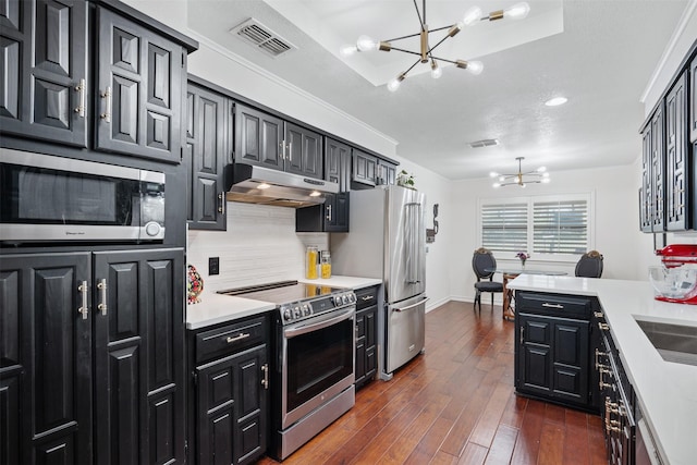 11721 Pine Creek Ct, Fort Worth, TX 76008 - kitchen featuring a chandelier, under cabinet range hood, appliances with stainless steel finishes, and dark cabinetry