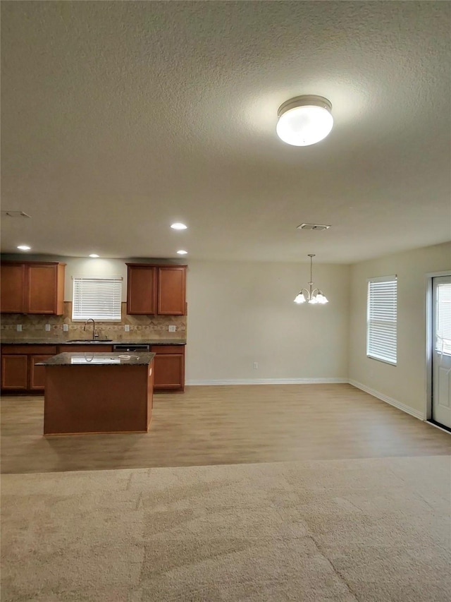 3116 Montserrat Creek Dr, Little Elm, TX 75068 - kitchen featuring dark countertops, decorative backsplash, a chandelier, a kitchen island, and open floor plan
